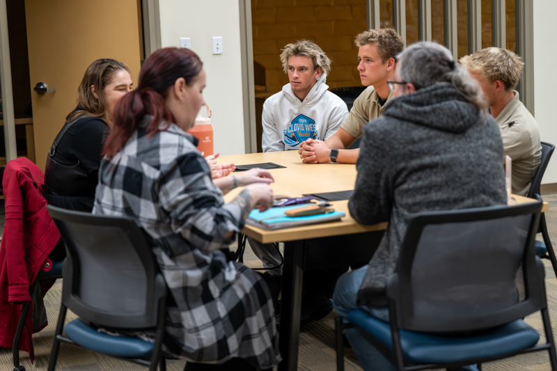 Six people sitting around a table Students and instructors sitting around a table
